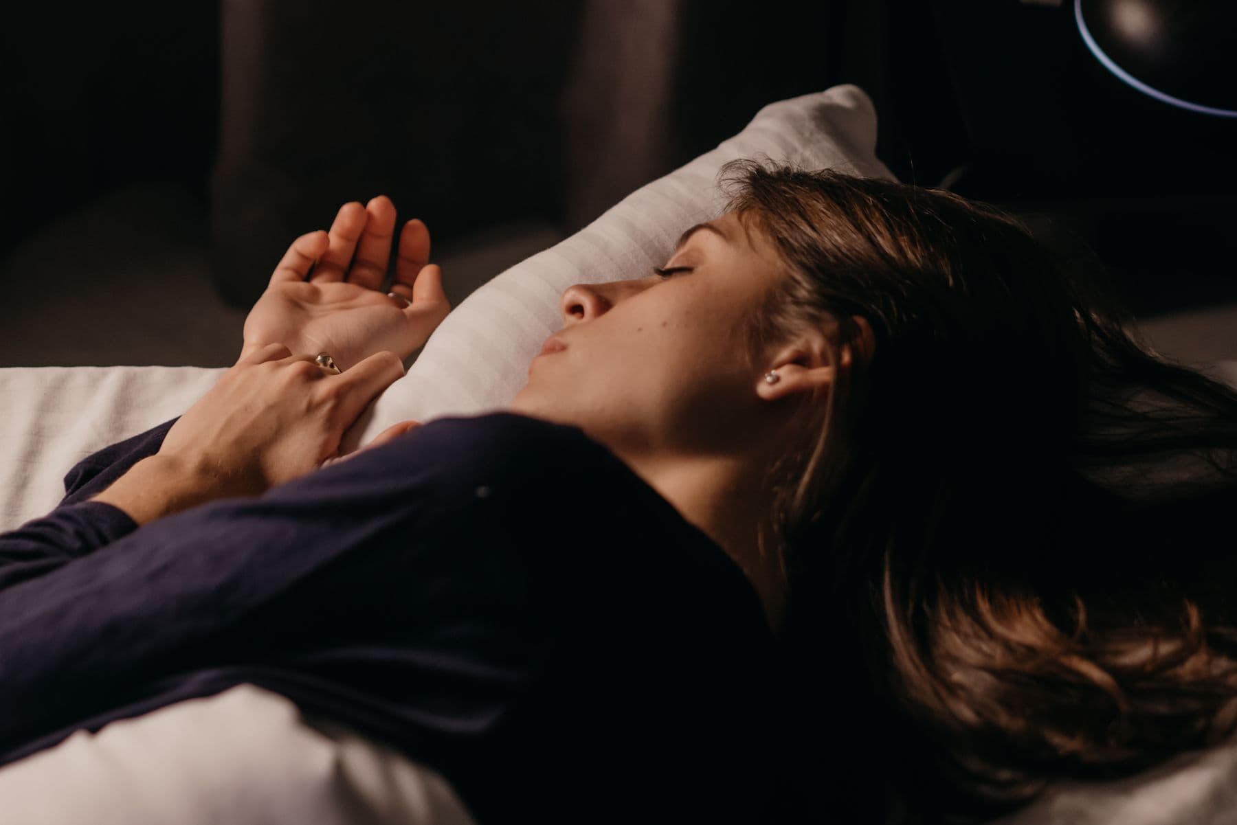 Žena pokojne spí na boku v prirodzene osvetlenej spálni